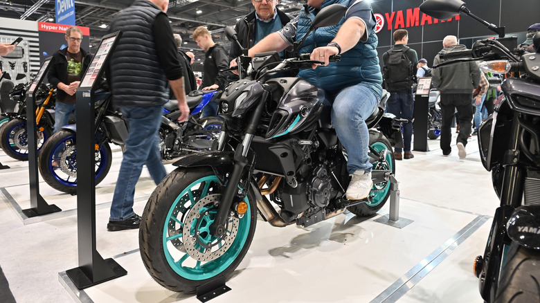 A visitor at a motor show sits extremely upright on a Yamaha MT07 adventure bike