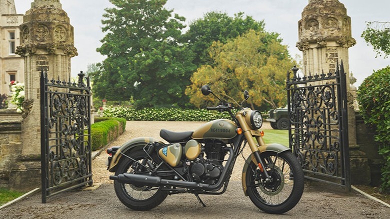 A yellow Royal Enfield Classic 350 parked in front of a gate