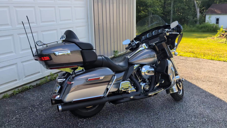A silver/grey 2014 Harley Davidson Electra Glide Ultra Classic motorbike parked outside the garage of a suburban home.
