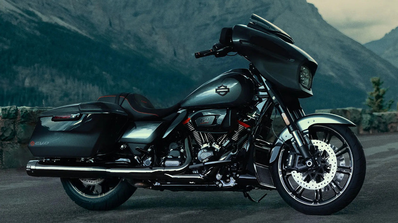 A black and silver 2025 Harley CVO Road Glide parked at the side of a road with mountains in the background in the evening