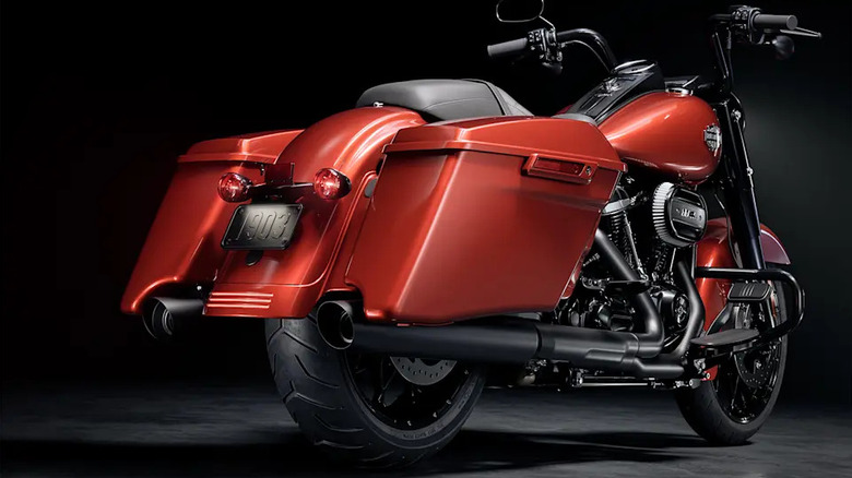 A red Harley Davidson Road King special parked against a black background, with massive rear saddlebags visible