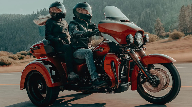 A red 2025 Harley-Davidson Trike Tri Glide Ultra with two riders on it in full gear