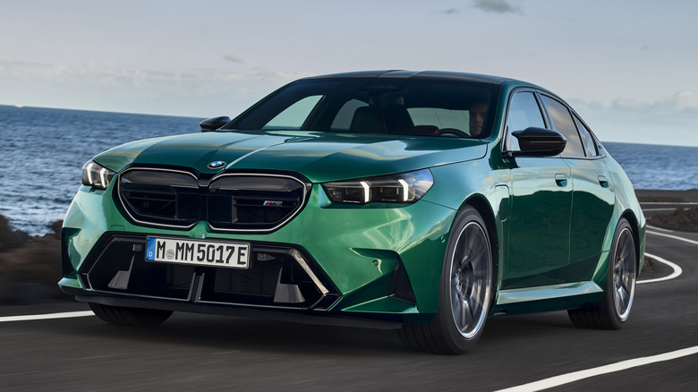 Green BMW M5 driving on a coastal road