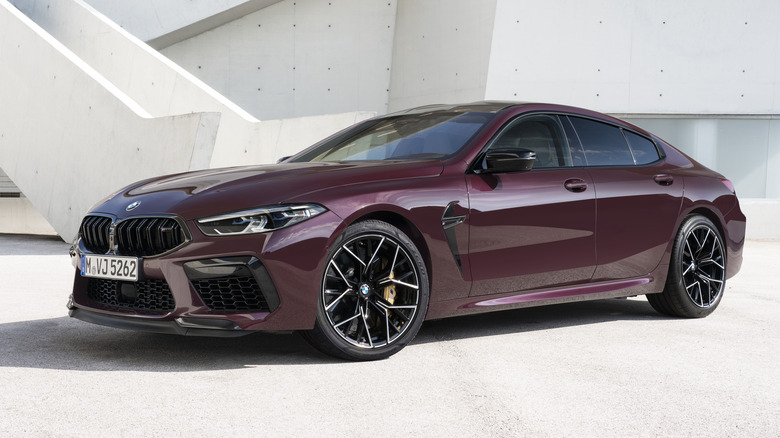 Maroon BMW M8 Competition Gran Coupé parked in front of a building
