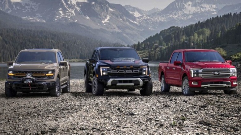 three Ford pick up trucks parked in front of a lake