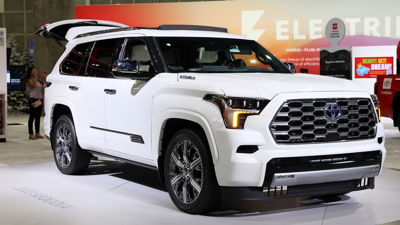 A white 2023 Toyota Sequoia on display at a dealership exhibition with its rear hatch open