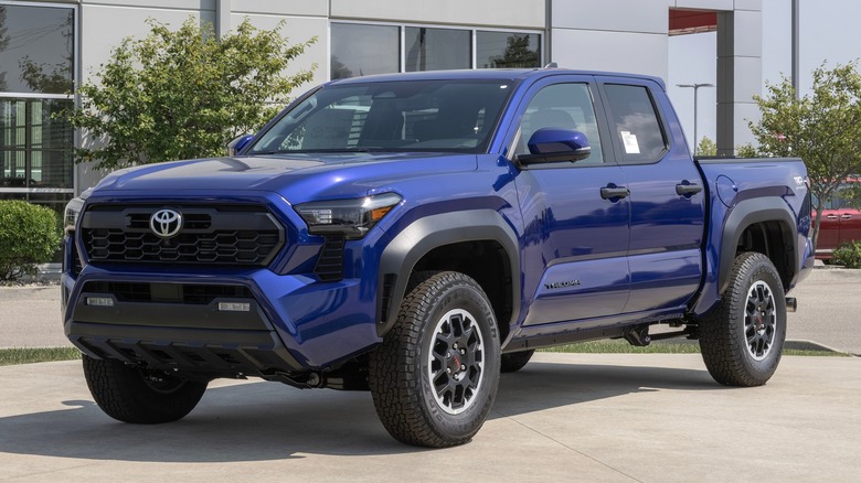 A blue Toyota Tacoma parked outside a dealership.