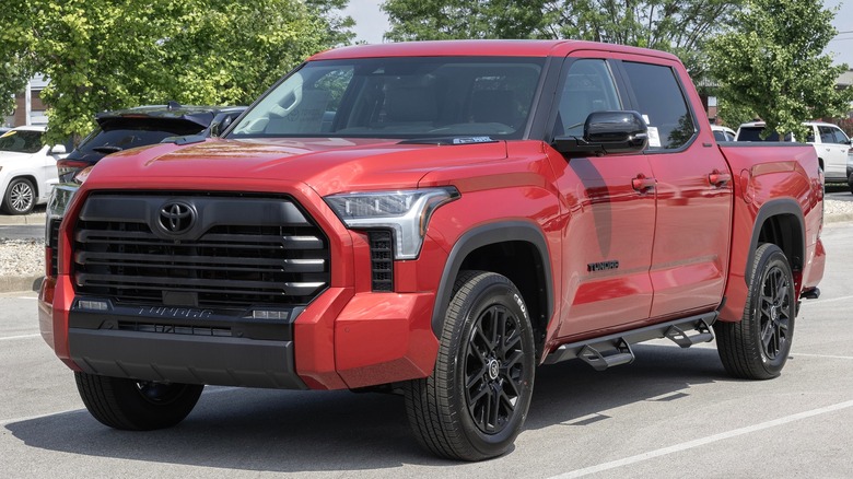 A red Toyota Tundra driving on a clear lane with traffic building up behind it