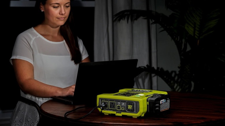 Person powering laptop with Ryobi power inverter