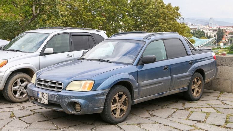 A grey Subaru Baja with dust all over it parked in a designated space