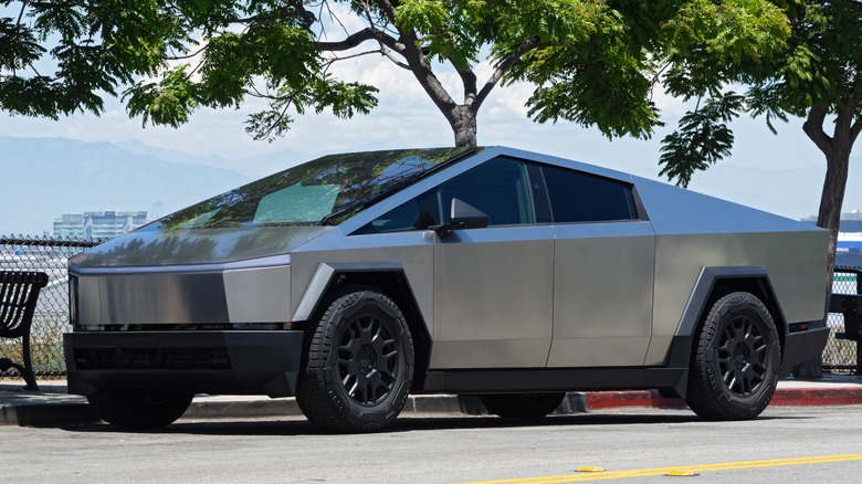 A stainless steel silver Tesla Cybertruck parked at the side of a city street in LA.
