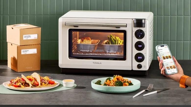 White toaster oven on a countertop surrounded by boxes and food dishes