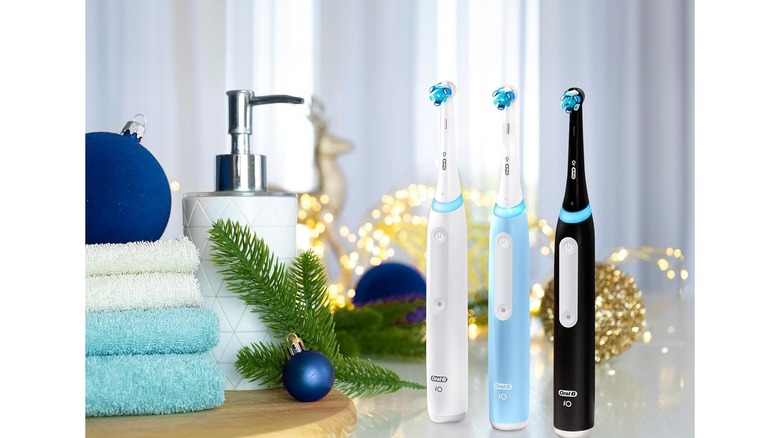 Three electric toothbrushes against a holiday-themed bathroom