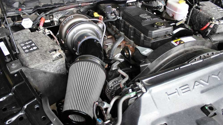 A Cummins diesel engine bay featuring a large aftermarket compound turbocharger and high-flow cone air filter.