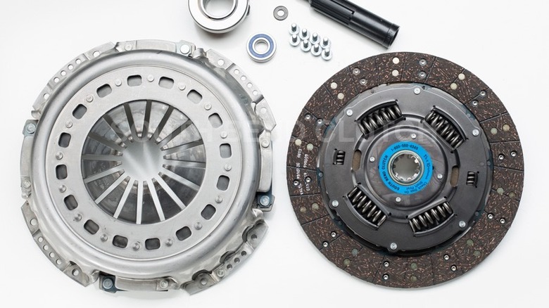 A South Bend Clutch clutch kit laid out on a white surface, including a pressure plate, clutch disc with springs, release bearing, pilot bearing, alignment tool, and hardware.
