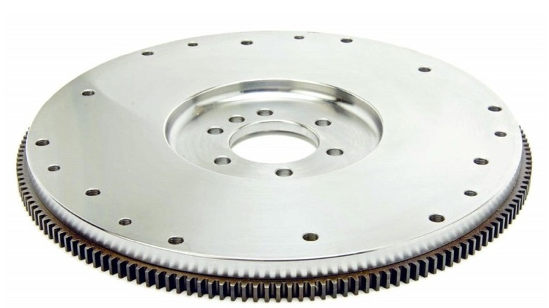 Polished steel automotive flywheel with evenly spaced bolt holes and a toothed ring gear around the outer edge.