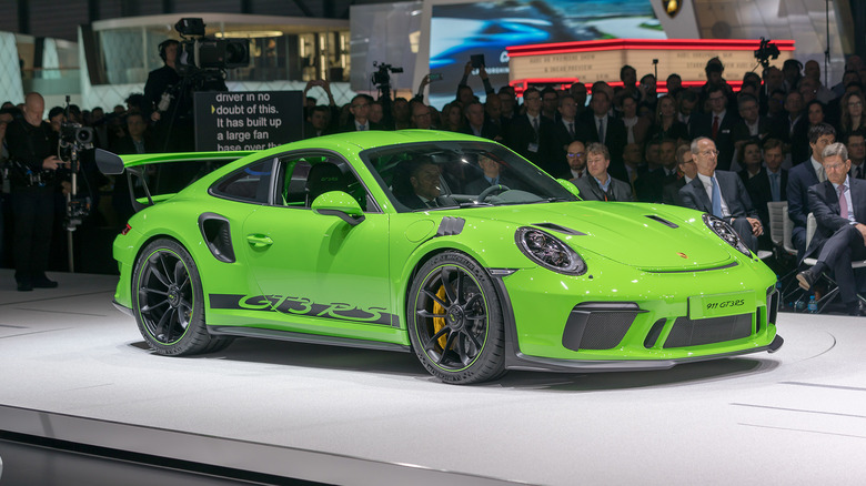 A green Porsche 911 GT3 RS at an auto show with many participants