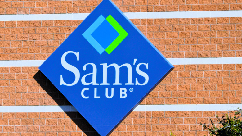 A diamond-shaped Sam's Club sign mounted to a red brick wall