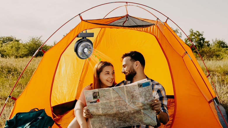 Two people in a tent with the Amacool Portable Camping Fan behind them.