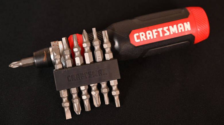 A Craftsman multi-bit screwdriver with its various bits against a black background