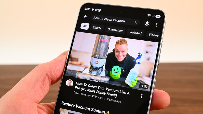 A Galaxy S26 Plus showing a YouTube video about cleaning vacuums.