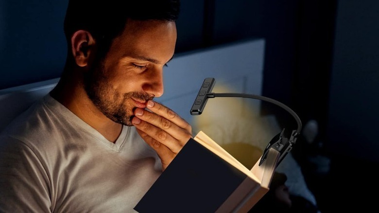 Person reading a book in bed with a Gritin book light illuminating the pages