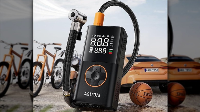 A portable inflator placed alongside a ball, bicycle, and a car.