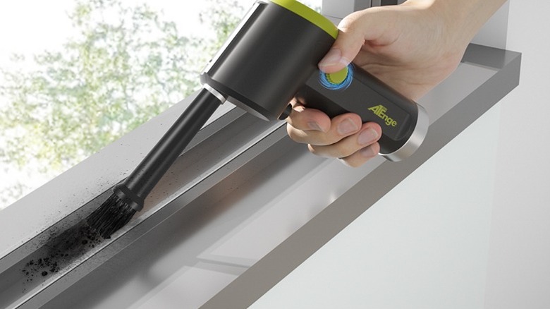 Using an air duster to clean between window sills.