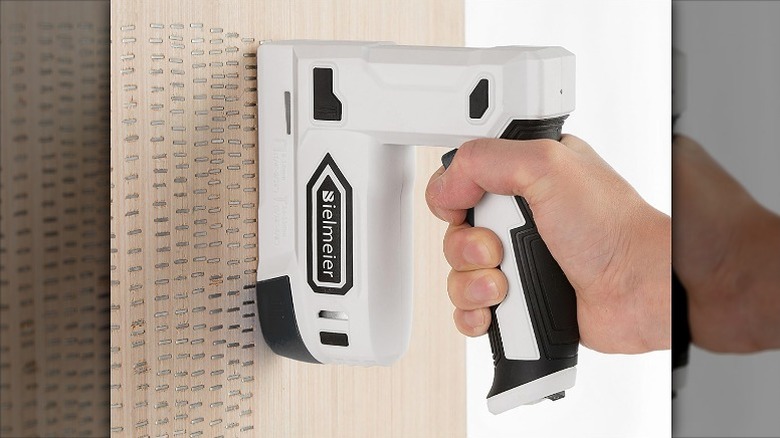 Using a stapler to staple a wooden surface.