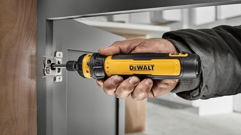 Using a DeWalt screwdriver to work on a fastener at a cabinet door.