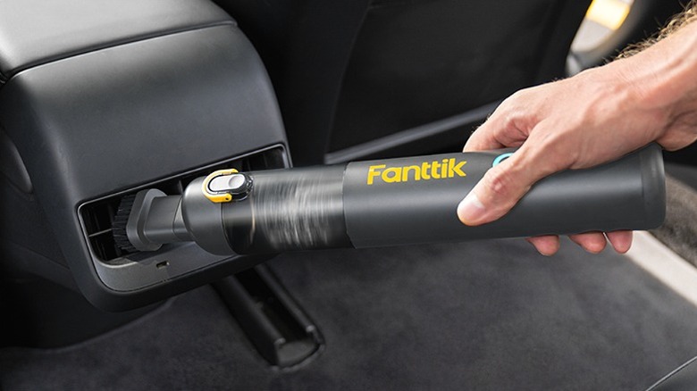 Using an air duster to clean AC vents in a car.