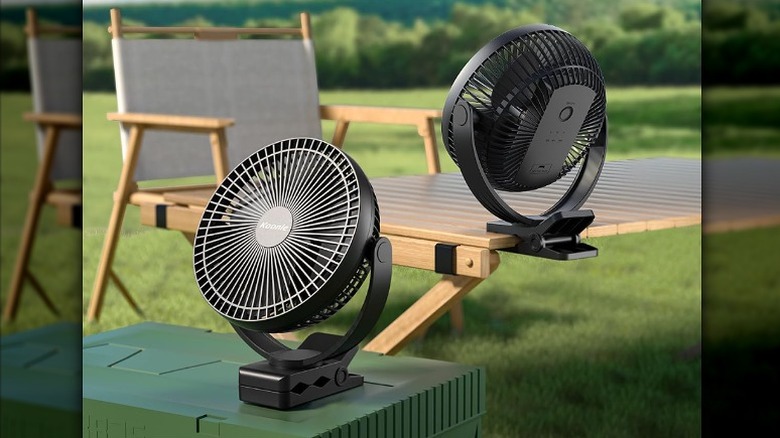 Two clip on fans mounted onto a table and a basket in a garden.