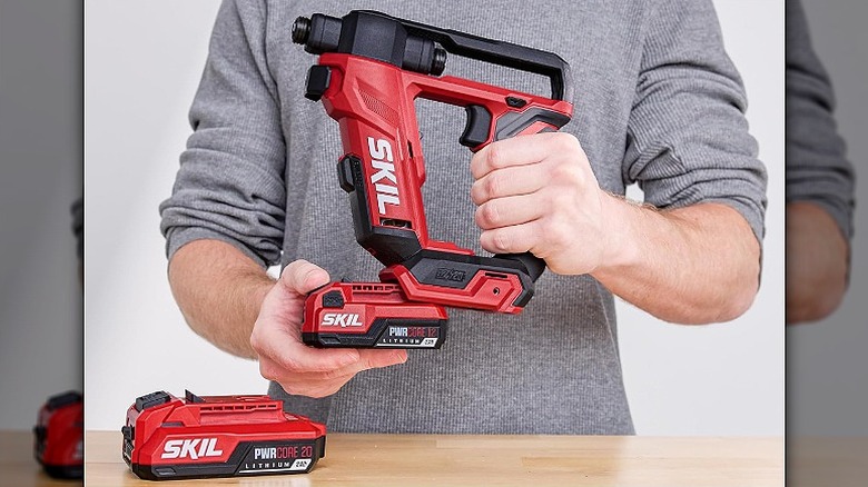 Loading a battery onto a cordless Skil drill driver.