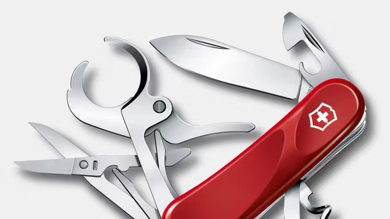 A red Swiss Army knife with several tools extended, including scissors, a corkscrew, a main blade, a can opener, and a cigar cutter.