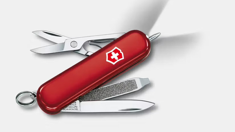 A red Signature Lite pen showing its pressurized ballpoint pen, light, and other tools.