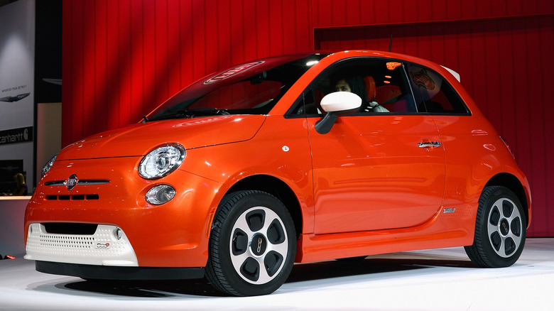 Orange Fiat 500e at auto show.