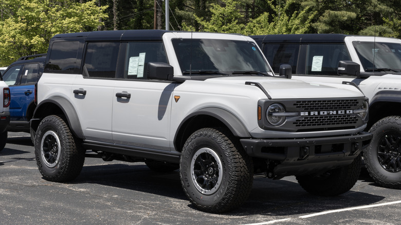 White and black Ford Bronco in a dealer lot.