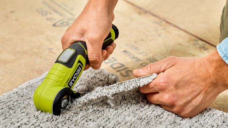 A person cutting carpet with a Ryobi power cutter