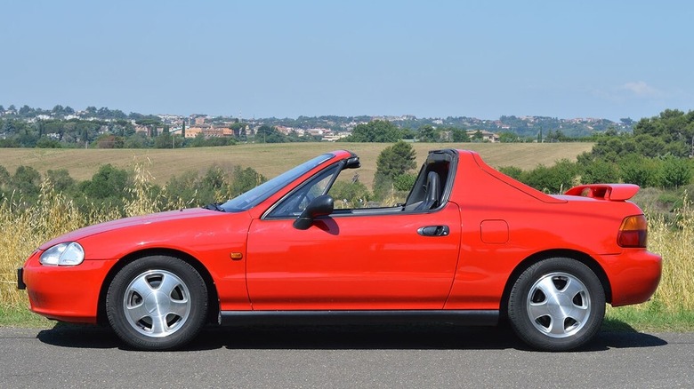 Red honda del sol in front of field