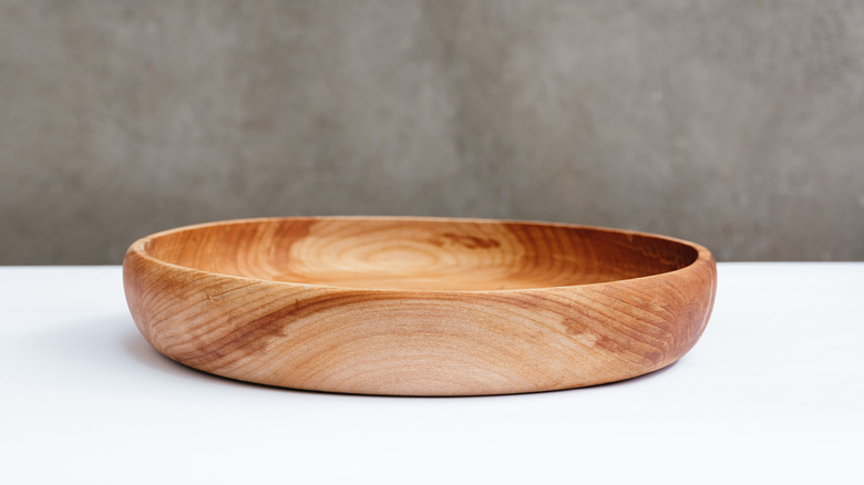 A light brown wooden bowl on a white table.