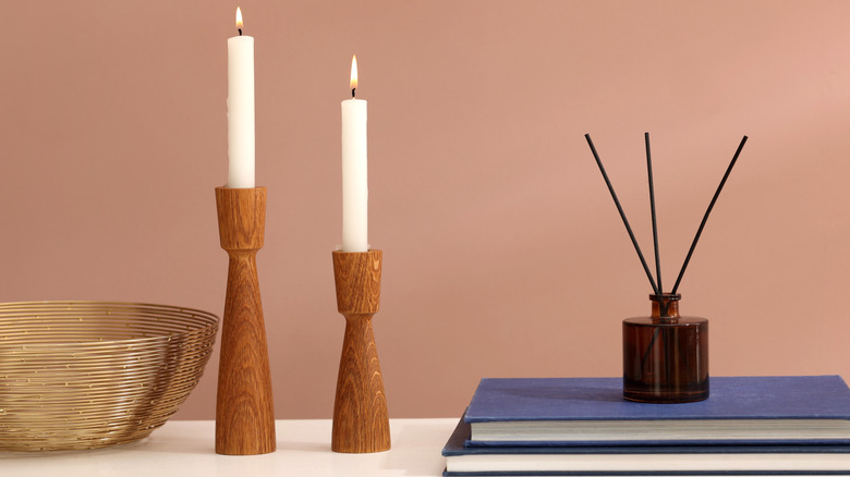 Two white candles held in the wooden candleholders on a table.