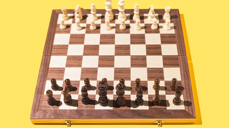 Chessboard with wooden pieces on a yellow backdrop