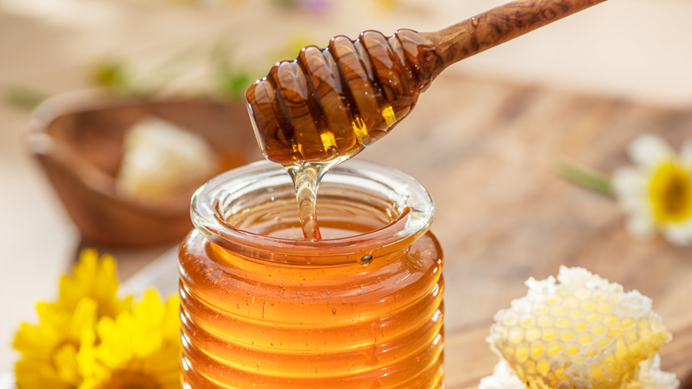 Honey dipper collecting honey from a jar