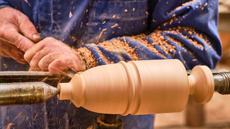 A person shapes wood on a wood lathe