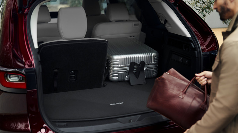 Man putting luggage into the trunk of a 2025 Mazda CX-90
