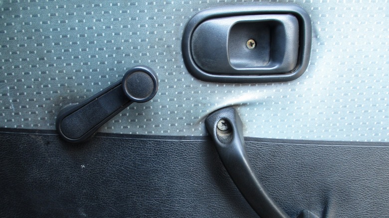 Close up of a car manual window crank and door handle