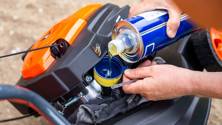 Person changing oil on push lawn mower