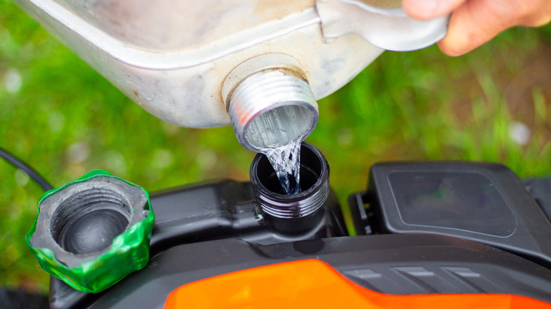 Person fueling gas-powered lawn mower