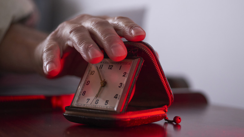 Someone closing a travel alarm clock.