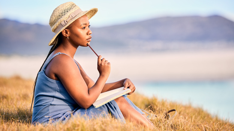 Shot of a young woman writing in her journal at the beach.